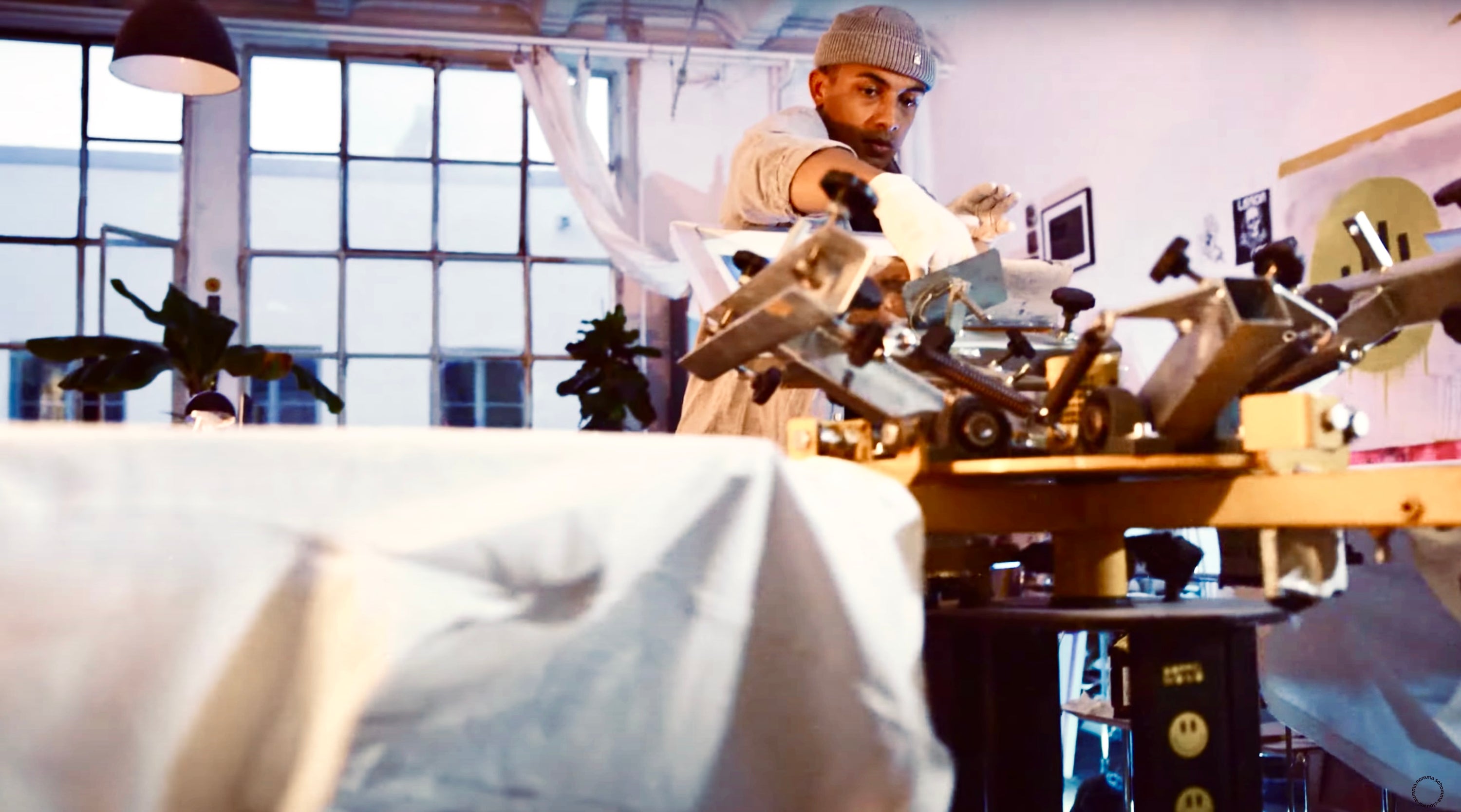 Clouwsi Co-Founder is printing t-shirts on a screen printing carousel